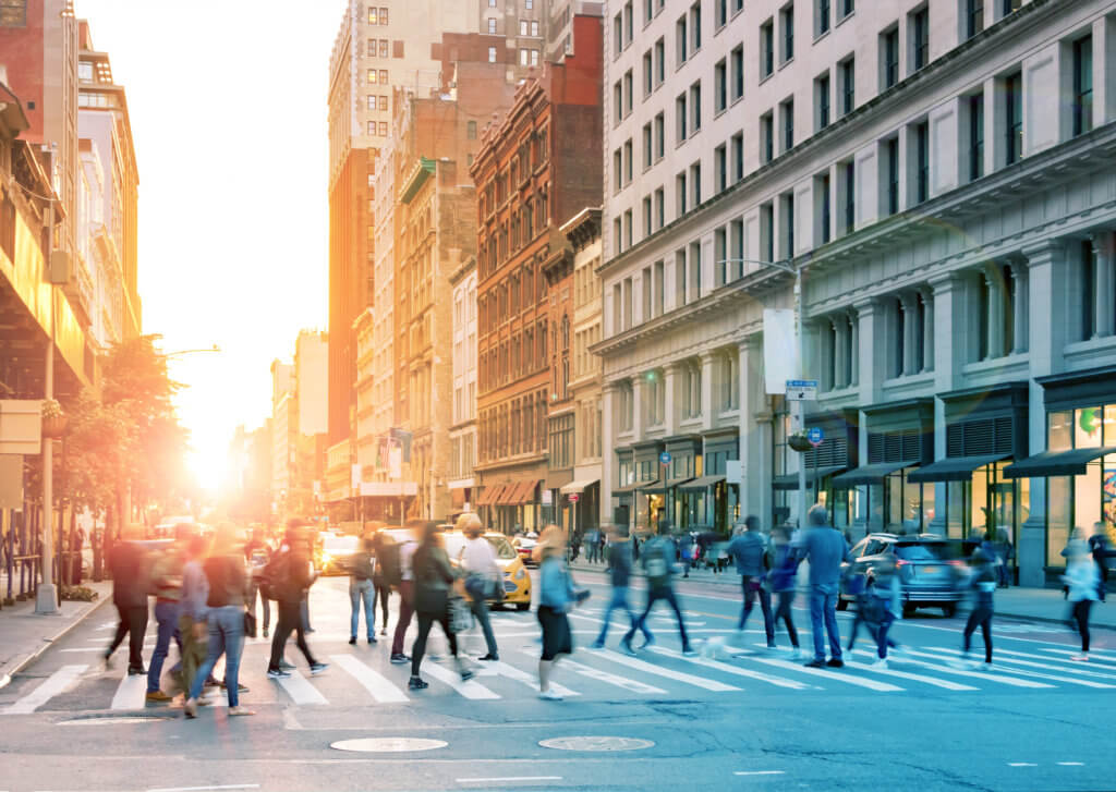 people walking across a crowded crosswalk in a city